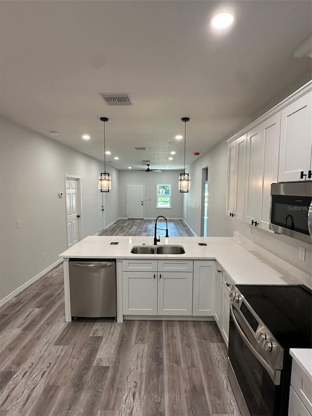 kitchen with decorative light fixtures, stainless steel appliances, sink, and white cabinetry