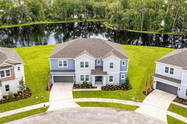 view of front of house with a garage, a water view, and a front lawn