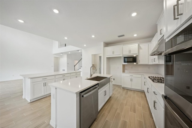 kitchen with a center island with sink, white cabinets, and appliances with stainless steel finishes