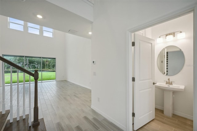 corridor featuring a towering ceiling and light hardwood / wood-style flooring