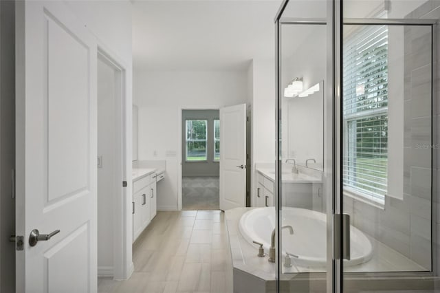 bathroom featuring plus walk in shower, vanity, and a wealth of natural light