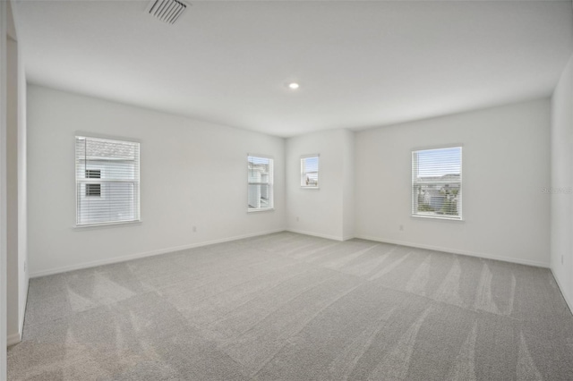 empty room featuring light colored carpet and a healthy amount of sunlight