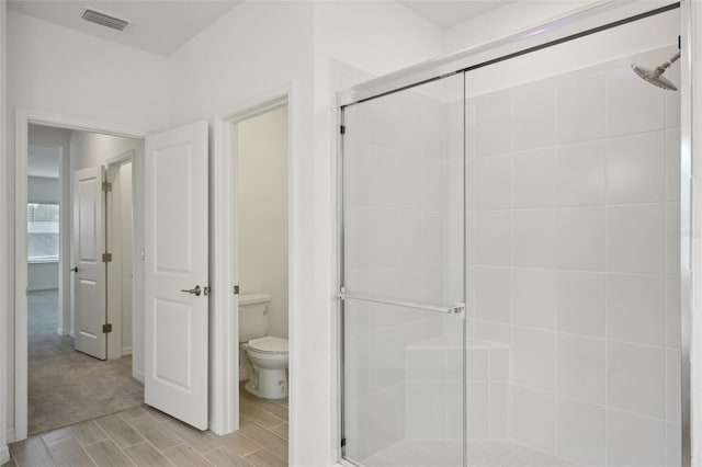 bathroom with toilet and an enclosed shower