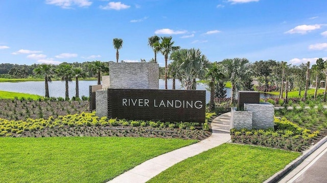 community sign featuring a yard and a water view