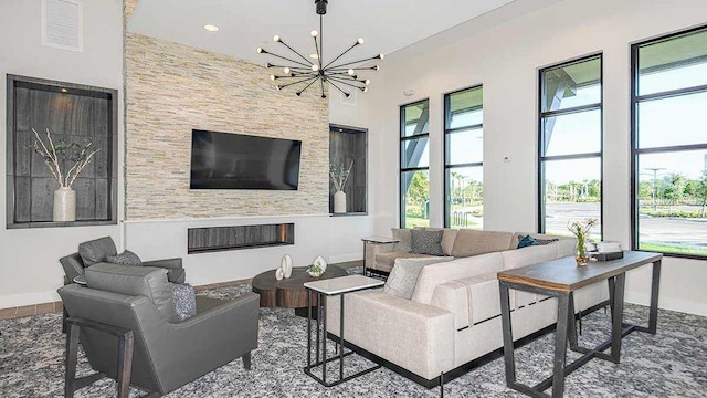 living room with a towering ceiling, a fireplace, and a chandelier