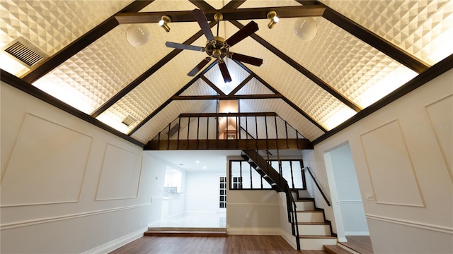 interior space featuring ceiling fan, hardwood / wood-style flooring, and a towering ceiling