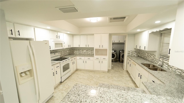 kitchen featuring independent washer and dryer, white cabinetry, white appliances, sink, and light stone countertops