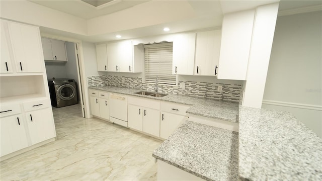 kitchen featuring decorative backsplash, light stone countertops, white dishwasher, sink, and washer / clothes dryer