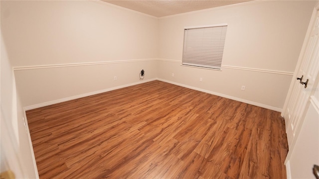 empty room with a textured ceiling, hardwood / wood-style flooring, and ornamental molding