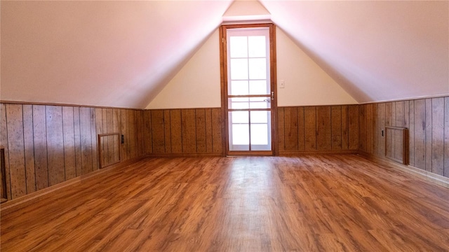 additional living space featuring wood walls, hardwood / wood-style flooring, and lofted ceiling