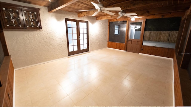 empty room featuring beamed ceiling, french doors, ceiling fan, light tile patterned floors, and wood ceiling