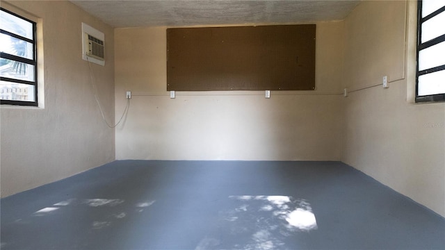 empty room with concrete floors, a wall mounted air conditioner, and plenty of natural light