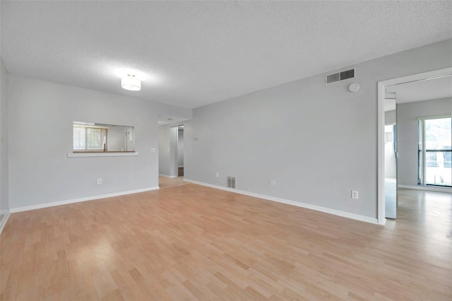 spare room with light hardwood / wood-style floors and a textured ceiling