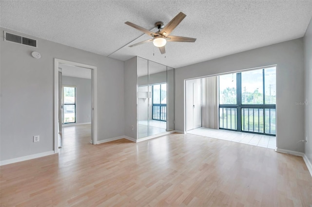 empty room featuring ceiling fan, a textured ceiling, and light hardwood / wood-style floors