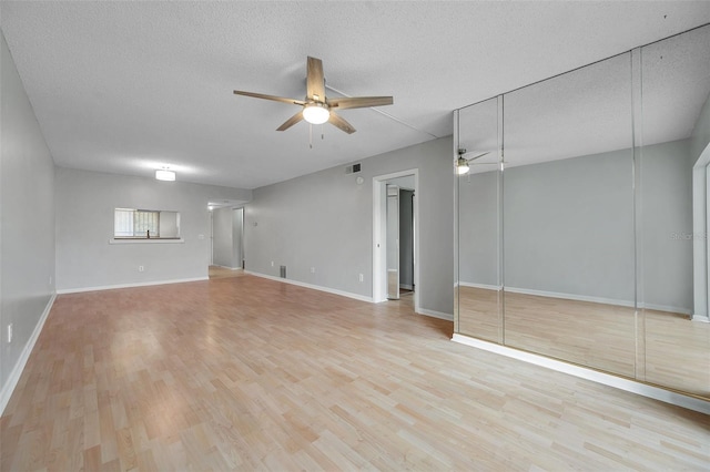 unfurnished living room featuring ceiling fan, a textured ceiling, and light wood-type flooring