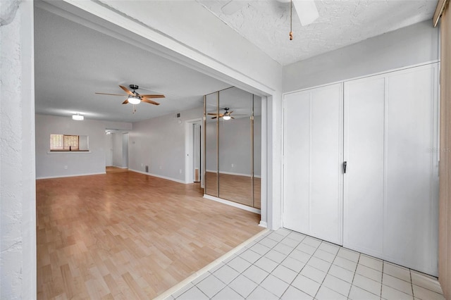 unfurnished living room featuring ceiling fan, light hardwood / wood-style floors, and a textured ceiling