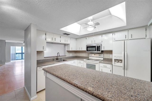 kitchen with sink, white appliances, white cabinets, and ceiling fan