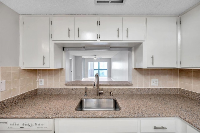 kitchen featuring sink, ceiling fan, white cabinetry, white dishwasher, and tasteful backsplash