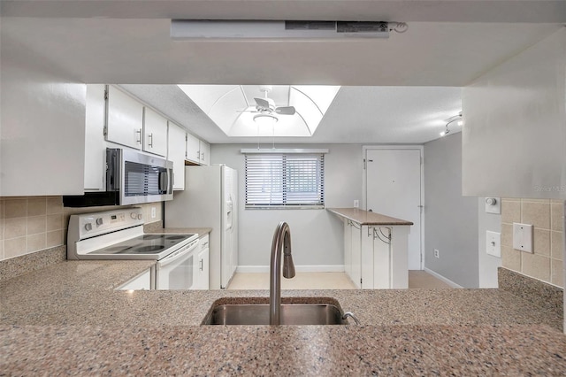 kitchen featuring sink, a tray ceiling, white appliances, decorative backsplash, and white cabinets