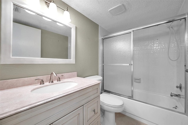 full bathroom with bath / shower combo with glass door, vanity, toilet, tile patterned floors, and a textured ceiling