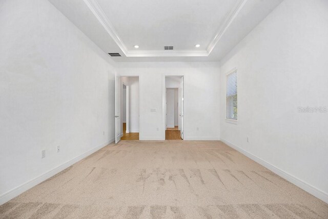 unfurnished bedroom featuring carpet, crown molding, and a tray ceiling