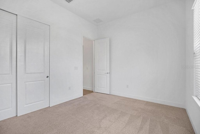 unfurnished bedroom with a closet and light carpet