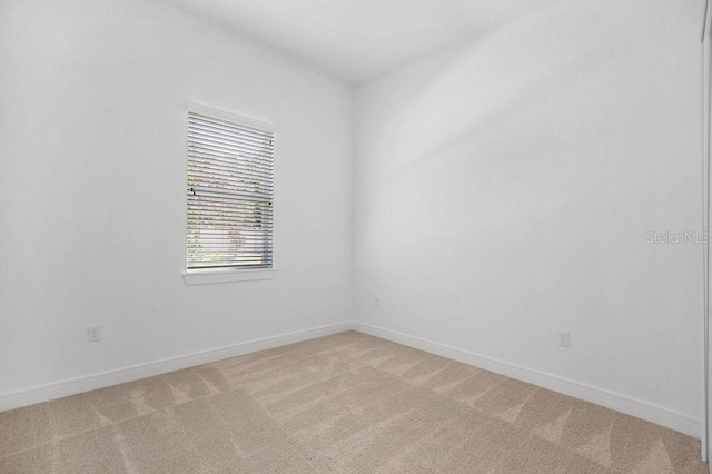 spare room featuring baseboards and light colored carpet