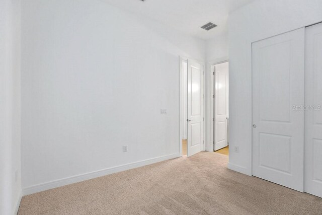 unfurnished bedroom featuring light carpet and a closet