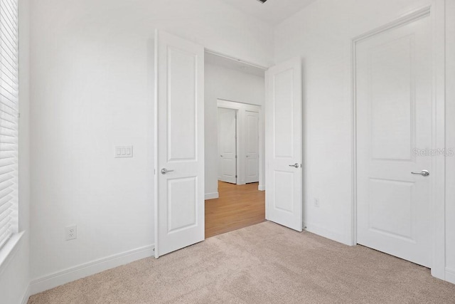 unfurnished bedroom featuring baseboards and light colored carpet