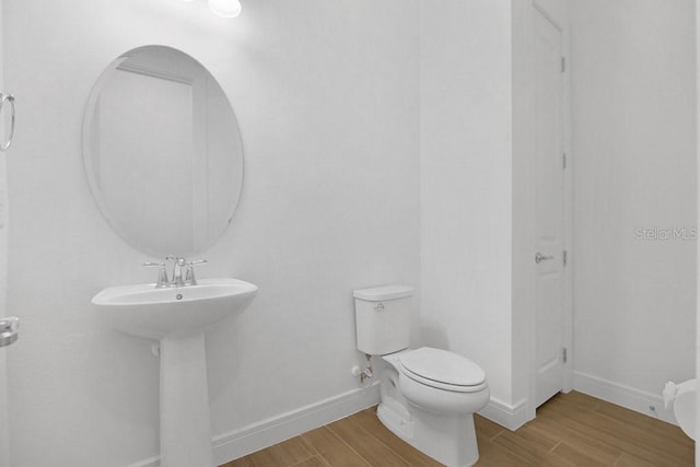 bathroom with baseboards, a sink, toilet, and wood finished floors