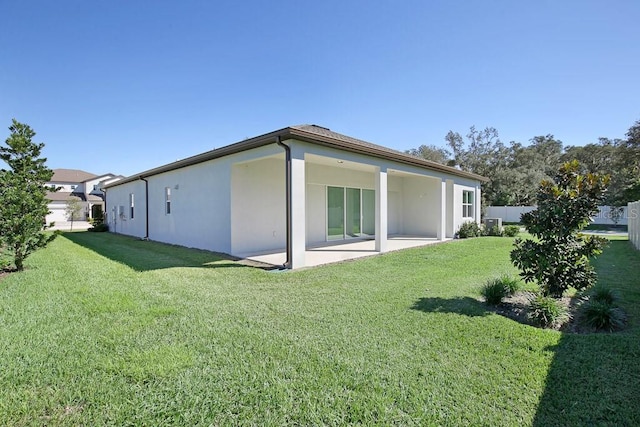 back of house featuring fence, a lawn, a patio, and stucco siding