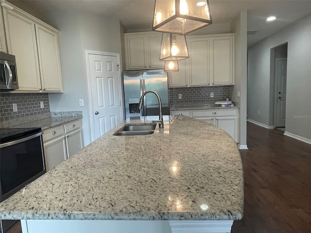 kitchen featuring a center island with sink, hanging light fixtures, appliances with stainless steel finishes, and sink