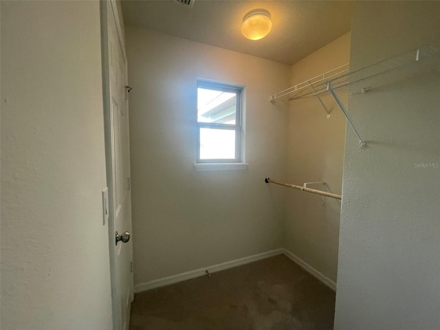 walk in closet with dark carpet