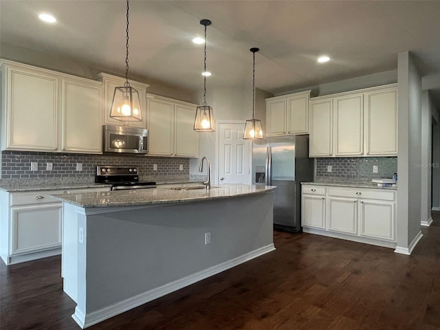 kitchen with appliances with stainless steel finishes, sink, light stone counters, pendant lighting, and a kitchen island with sink