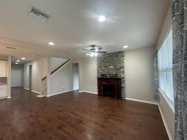 unfurnished living room featuring dark hardwood / wood-style flooring, ceiling fan, and a large fireplace