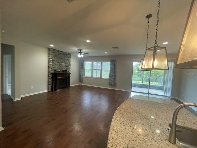 unfurnished living room with a fireplace, sink, dark hardwood / wood-style floors, and ceiling fan