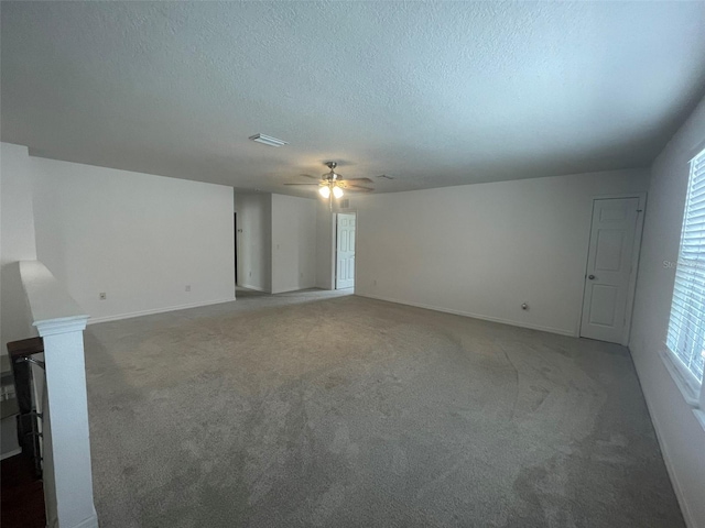 empty room featuring a textured ceiling, dark carpet, and ceiling fan