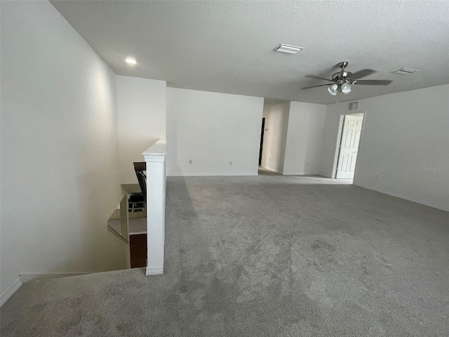 carpeted spare room featuring ceiling fan and a textured ceiling