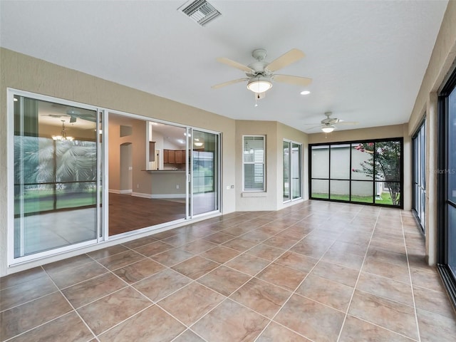 unfurnished sunroom featuring visible vents, arched walkways, and ceiling fan with notable chandelier