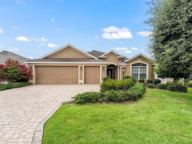 ranch-style home with a garage, a front yard, decorative driveway, and stucco siding