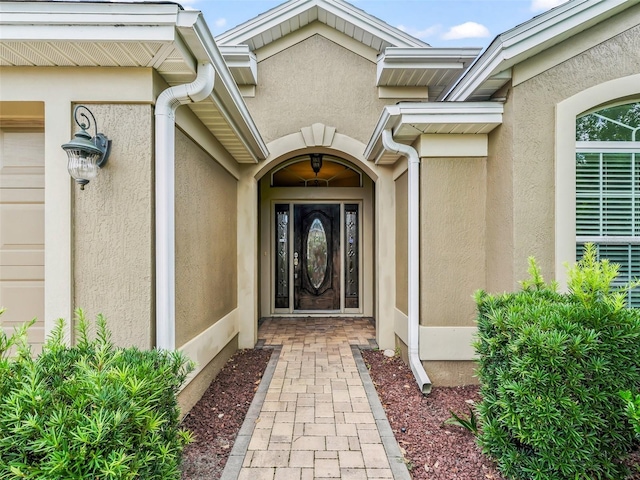 view of exterior entry featuring a garage and stucco siding