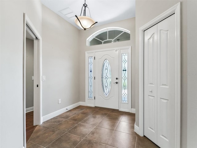 entryway with dark tile patterned flooring and baseboards