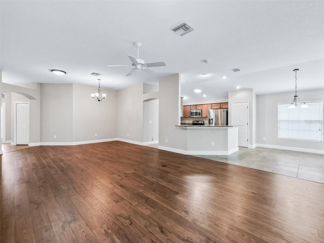 unfurnished living room with visible vents, arched walkways, baseboards, light wood-type flooring, and ceiling fan with notable chandelier