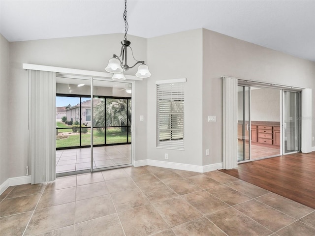 tiled empty room with lofted ceiling, baseboards, and an inviting chandelier