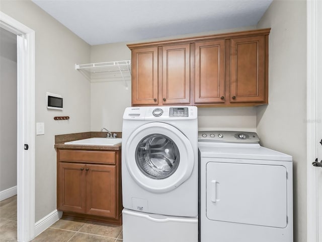 laundry room with cabinet space, baseboards, independent washer and dryer, a sink, and light tile patterned flooring