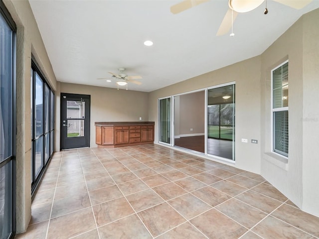 unfurnished sunroom featuring a ceiling fan