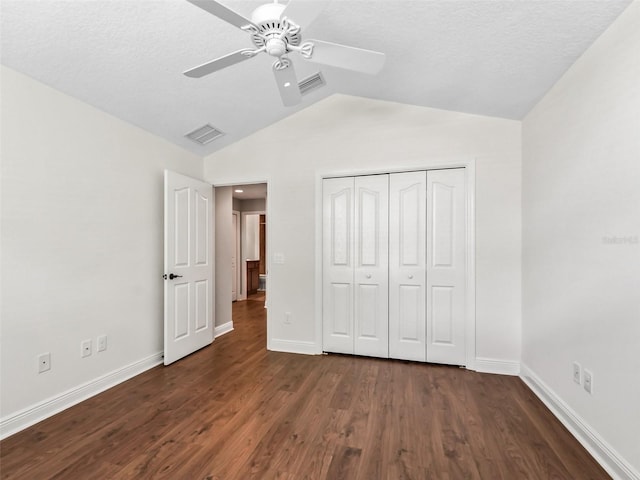 unfurnished bedroom featuring vaulted ceiling, visible vents, dark wood finished floors, and baseboards