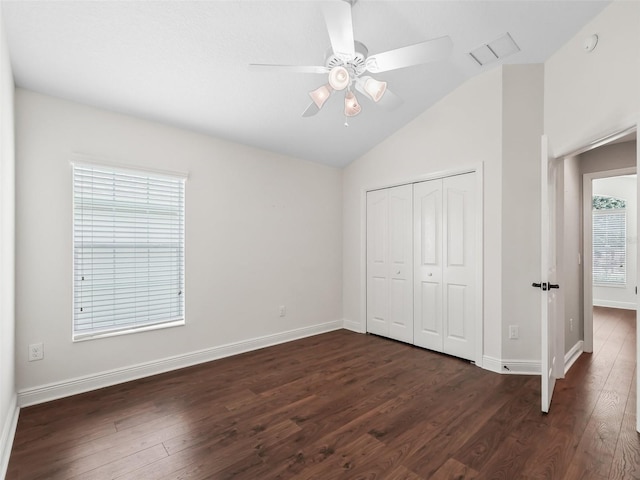 unfurnished bedroom with dark wood finished floors, a closet, vaulted ceiling, and baseboards