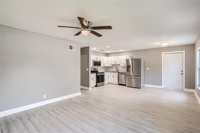 kitchen with white cabinets, light hardwood / wood-style flooring, ceiling fan, tasteful backsplash, and stainless steel appliances