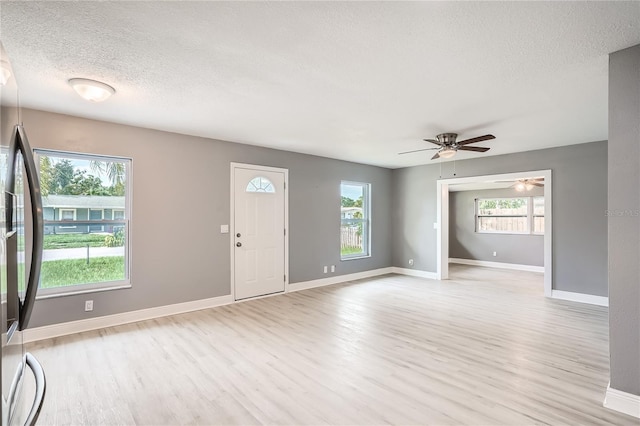 unfurnished living room featuring a textured ceiling, light hardwood / wood-style floors, a wealth of natural light, and ceiling fan